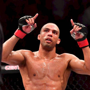 一位勝利的MMA拳手在八角籠內舉起手指慶祝。 — 冠軍 壁紙