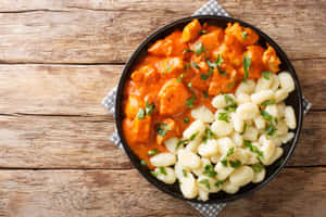 木桌上黑色碗中的馬鈴薯糰子和雞肉咖喱。 — 美食 壁紙