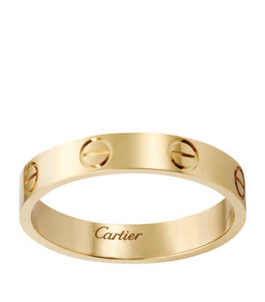 一枚黃金Cartier love戒指，帶有螺絲圖案和刻印品牌名稱。