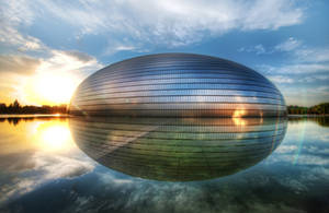 金色夕陽下，未來風格的玻璃圓頂建築倒映在水中。 — 中國 壁紙
