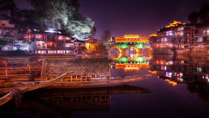 傳統中國河邊小鎮夜景，燈籠和木船。