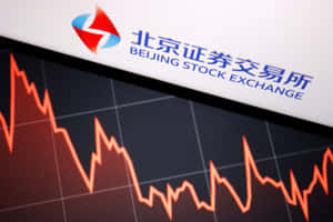 北京證券交易所標誌位於屏幕上顯示下跌的股票市場圖表上方。 — 中國 壁紙
