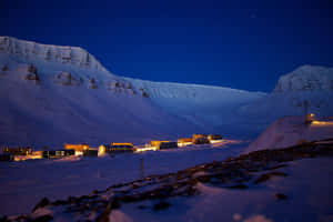 白雪覆蓋的山村在繁星點點的夜空下被溫暖的燈光照亮。