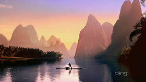 夕陽下，漁夫在竹筏上划過平靜的河流，周圍環繞著高聳的山峰。