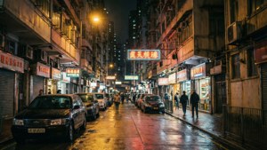 夜晚的城市街道，霓虹燈牌倒映在濕漉漉的路面上，有行人走過。