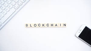 白色辦公桌上，用木製瓷磚拼出blockchain，旁邊有鍵盤和電話。