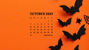 2021年10月萬聖節日曆，橙色背景上有紙蝙蝠、蜘蛛和蜘蛛網。