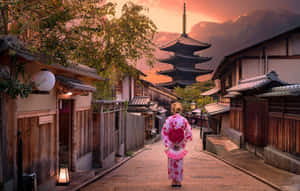 身穿粉紅色和服的女士在日落時分的日本街道上走向寶塔。 — 日本 壁紙