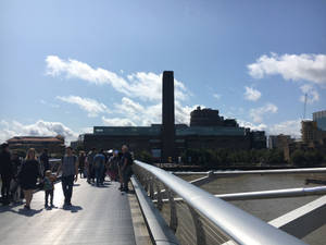 人群走過河邊的金屬橋，背景是博物館。 — 城市 壁紙