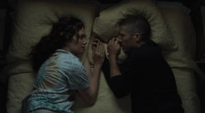兩個人在昏暗的房間裡躺在床上握著手。 — 暮光 壁紙