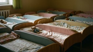一排排空的幼兒床，配有毛毯和毛絨動物，在育嬰室中。