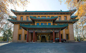 宏偉的中式建築，青綠色屋頂和紅色柱子，被秋樹環繞。 — 唐人街 GIF 壁紙