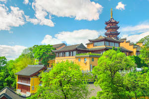 藍天白雲下，綠樹環繞的黃色寶塔和寺廟。 — 唐人街 GIF 壁紙