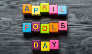 色彩繽紛的積木在深色木頭上拼出April Fools Day。