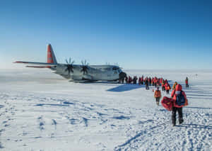 身穿紅色裝備的人們在雪原上走向一架美國空軍飛機。
