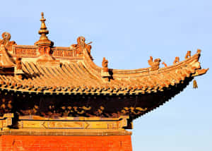 藍天下，傳統中國寺廟的屋頂，鋪著金色瓦片，裝飾著脊獸。