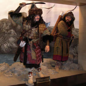 兩個身穿毛皮和盔甲的戰士人體模型在博物館立體模型中手持武器。 — 電影 GIF 壁紙
