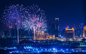 煙火在夜晚燈火通明的城市上空綻放。 — 煙火 壁紙
