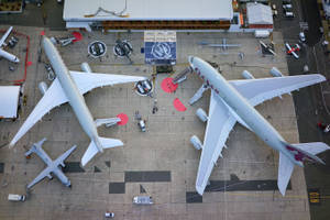 兩架卡塔爾航空飛機停泊在機場停機坪，有地勤人員和車輛。