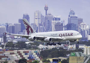卡塔爾航空A380飛機在港口附近降落，背景為城市天際線 — 城市景觀 壁紙