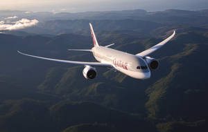 卡塔爾航空飛機在日落時分飛越綠色山脈