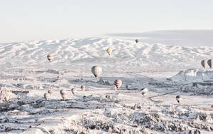 熱氣球漂浮在白雪覆蓋的山區上空。