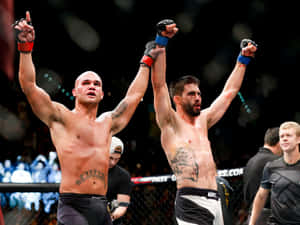 兩位赤裸上身的MMA拳手在八角籠內高舉雙臂慶祝勝利。