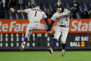 兩名棒球運動員在夜間燈光球場上跳躍慶祝。