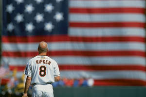 穿著Ripken 8球衣的棒球運動員站在美國國旗前。 — 美國國旗 壁紙