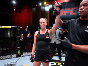 女性MMA拳手在UFC八角籠內由裁判舉起手慶祝勝利。 — 4:3 壁紙