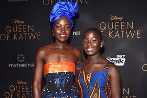 兩位穿著色彩繽紛傳統裙子的女性在《Queen of Katwe》電影首映禮上微笑。 — 你的名字 壁紙