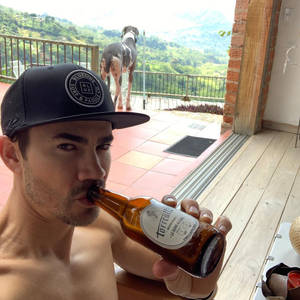 男人在陽台上喝啤酒，狗望著山丘 — 運動 壁紙