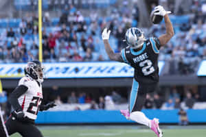 外接手在NFL比賽中跳起接住橄欖球，防守球員在附近。