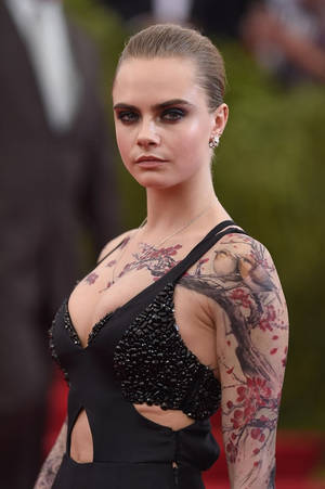 Cara Delevingne 身穿黑色珠飾連衣裙，手臂上紋有櫻花圖案。