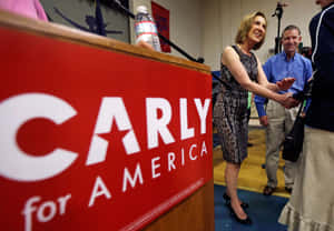 Carly Fiorina 在競選集會上握手，前方有紅色講台。