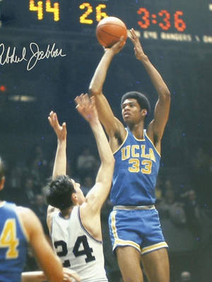 比賽中，UCLA籃球運動員33號在防守球員24號上方投籃。