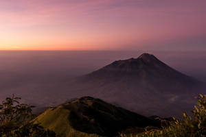 黃昏時分的火山，粉紅色和紫色的天空，霧氣瀰漫的山谷