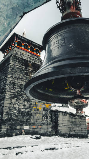 一個大型寺廟鐘掛在雪覆蓋的石塔前。 — 廟宇 壁紙