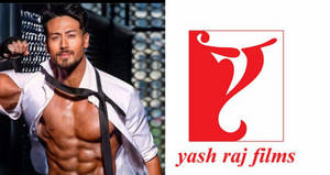 一個赤裸上身的男人脖子上繫著領帶，站在Yash Raj Films標誌旁邊。