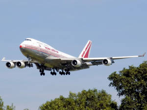 印度航空波音747飛機降落，下方有樹木，上方有藍天。