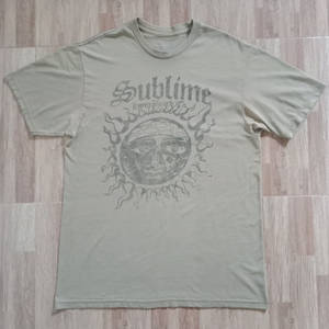 淺色木地板上的橄欖綠色 Sublime 樂隊 T 恤