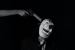 一個戴面具的人在黑暗環境中面對由手臂握著的槍。 — 鬼滅之刃面具 壁紙