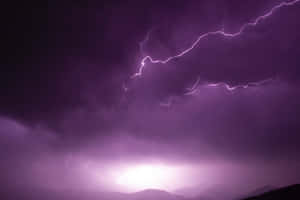 紫色閃電照亮了山脈剪影上方的暴風雨夜空。