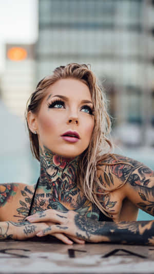 紋身女性在日落時分的城市環境中向上看。