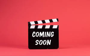 珊瑚粉紅色背景上帶有 'COMING SOON' 文字的場記板