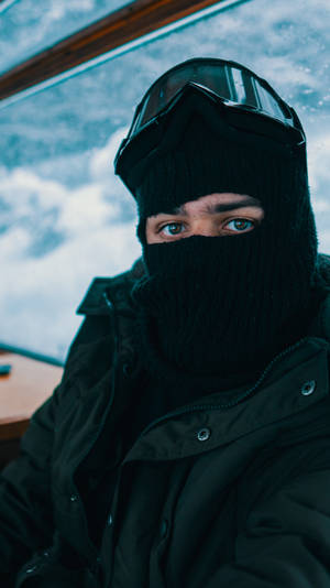 戴黑色巴拉克拉法帽和護目鏡的人望向雪窗外