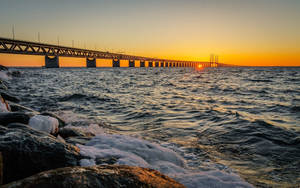 日落時分，長橋上方的夕陽，伴隨著冰岩和波濤洶湧的海水。