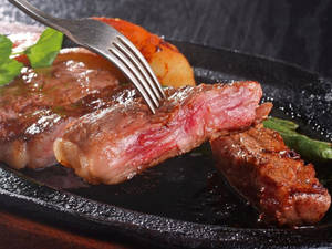 切開嘅 medium-rare 牛扒配烤薯仔同蘆筍，擺喺黑色碟上。