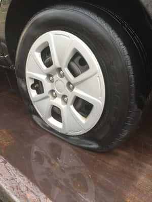 潮濕木質表面上的扁平汽車輪胎與銀色輪圈。