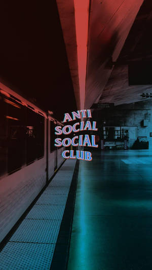 在昏暗的地鐵站中，一個寫著「ANTI SOCIAL SOCIAL CLUB」的霓虹標誌。